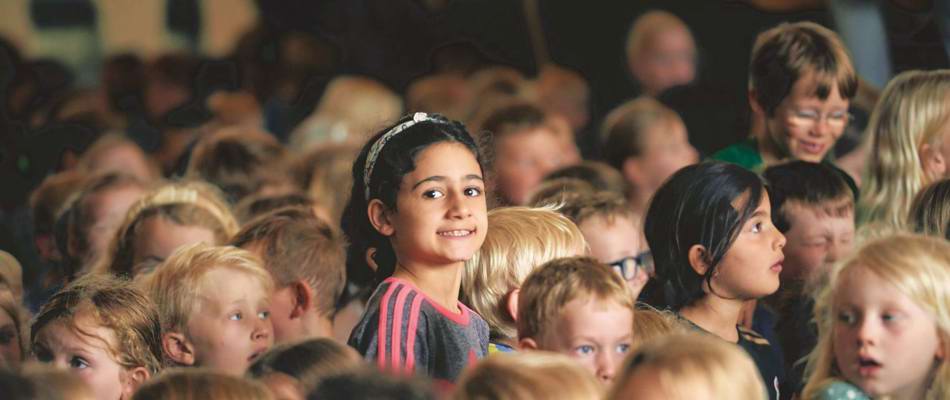 Pige i forsamling kigger på kameraet