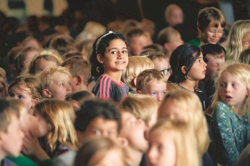 Pige i forsamling kigger på kameraet